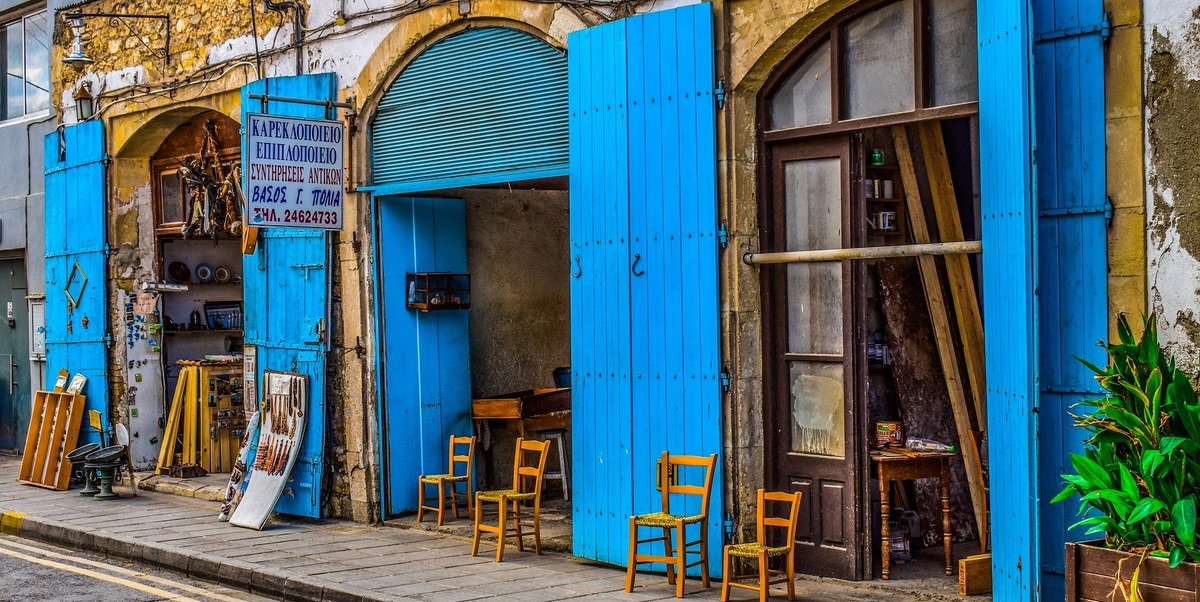 Chipre. Tienda tipica con portalones azules abiertos y sillas en la acera en Larnaca, Chipre