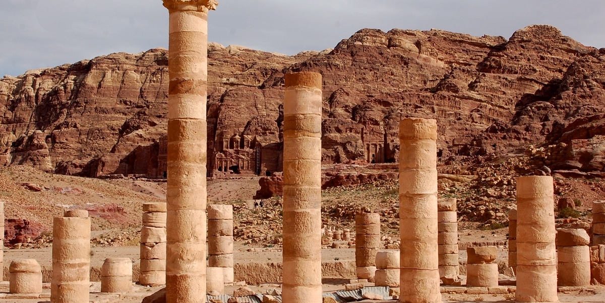 Jordania. Restos de una columnata frente a varias fachadas clásicas esculpidas en la roca en Petra, Jordania