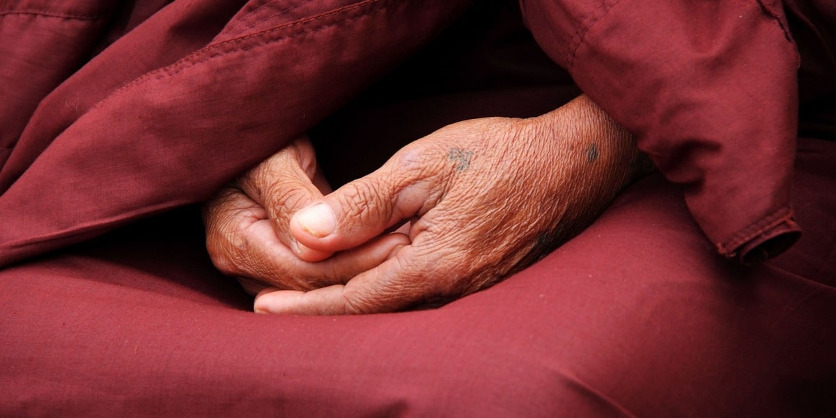 Laos. Manos de monje en el regazo en posición de meditación en Laos