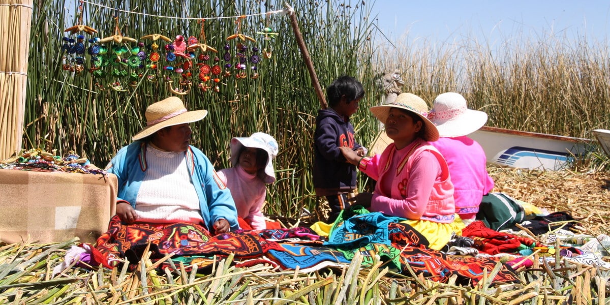 Perú. Mujeres en la isla de los Uros, Puno y Titicaca, sentadas en el suelo y al sol trabajando en diferentes tejidos y bordados, en Perú