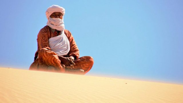 Argelia. Tuareg envuelto en sus ropajes en la cima de una duna del desierto del Sahara cerca de Tassili N'Ajjer en Argelia