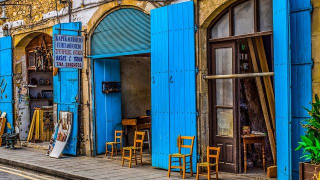 Chipre. Tienda tipica con portalones azules abiertos y sillas en la acera en Larnaca, Chipre