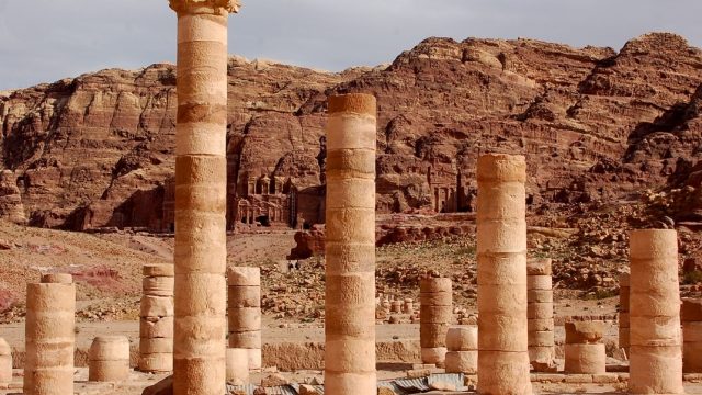 Jordania. Restos de una columnata frente a varias fachadas clásicas esculpidas en la roca en Petra, Jordania